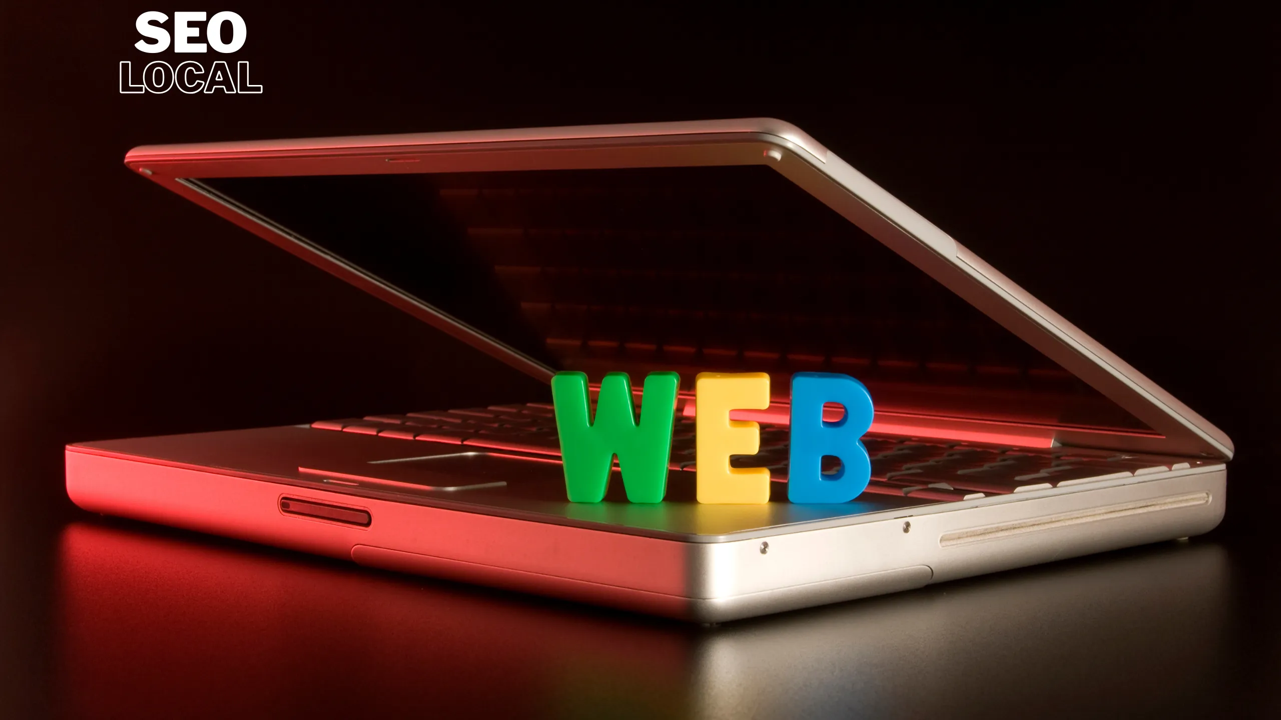 Un portátil abierto con la palabra WEB en letras de colores sobre el teclado, que representa la revisión de una página web