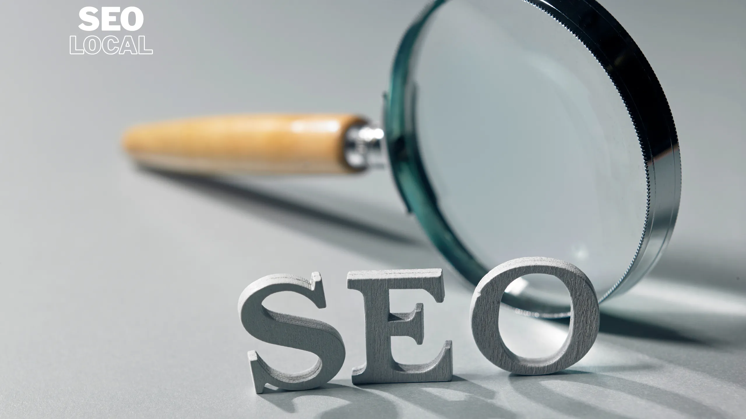 Una lupa sobre la palabra SEO sobre una superficie gris, que representa la revisión de una página en una auditoría