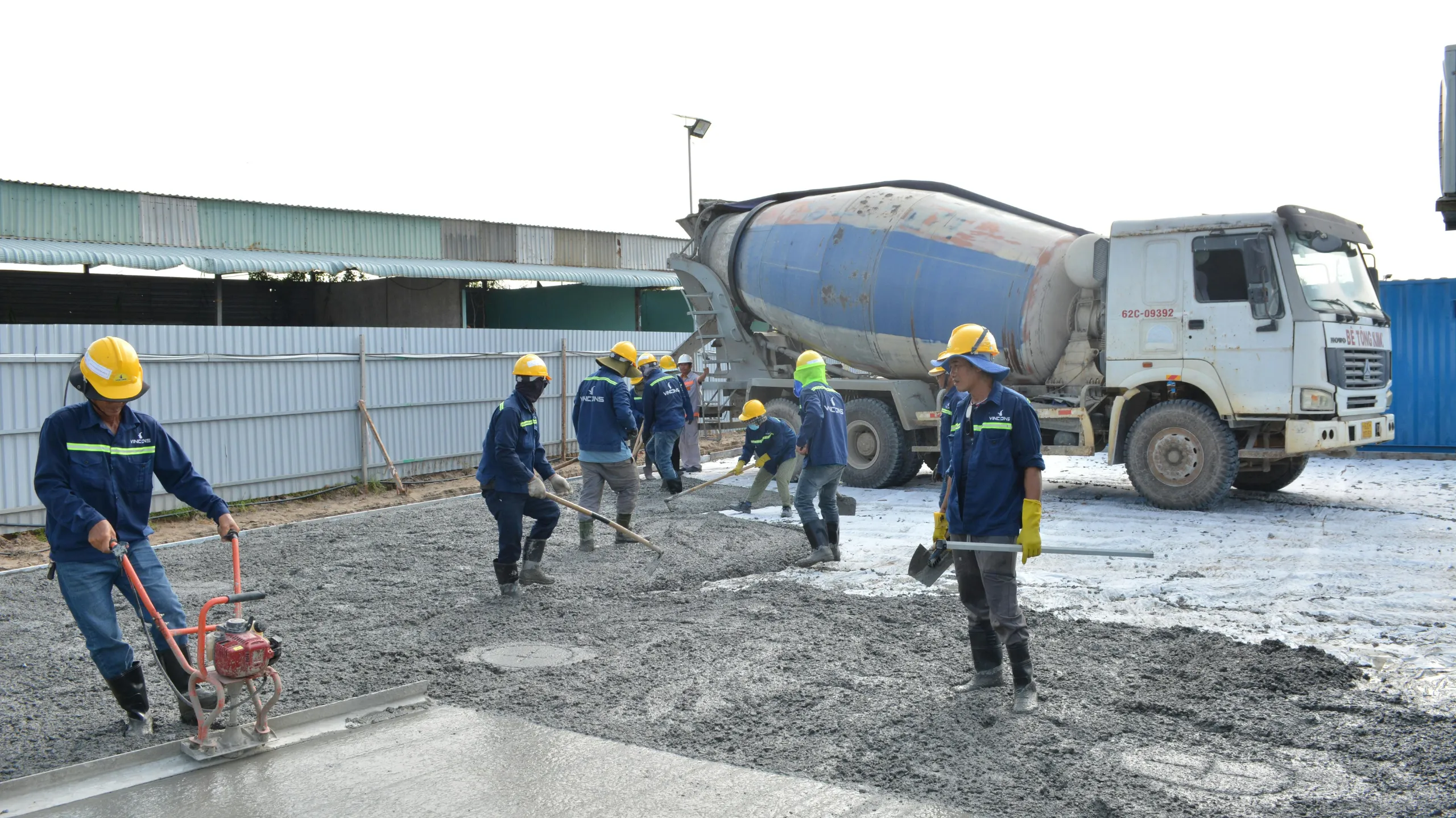 Un camión mezclador de concreto y obreros trabajando en una placa