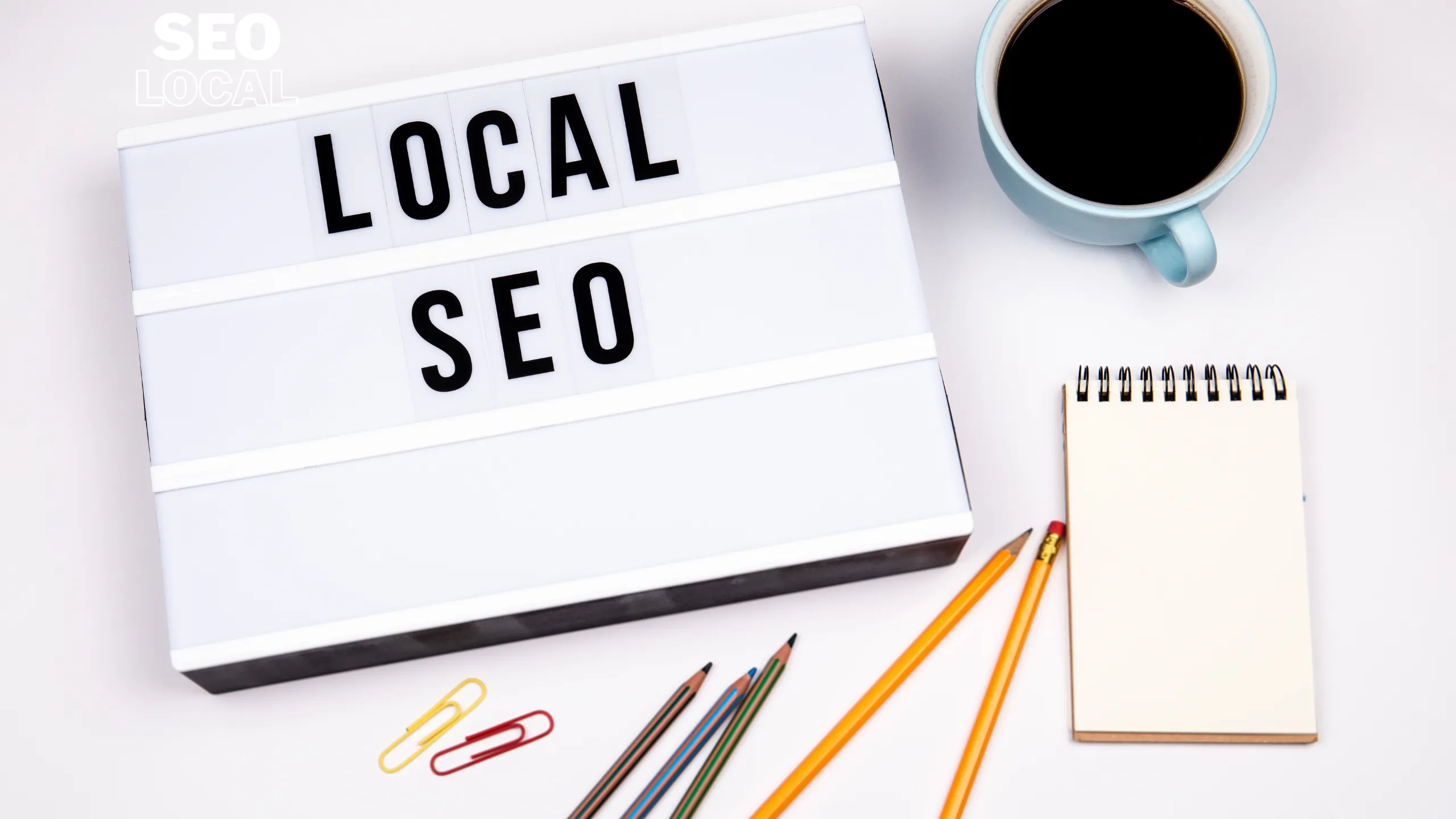 Un letrero con las palabras local SEO sobre un escritorio con un cuaderno y una taza de café