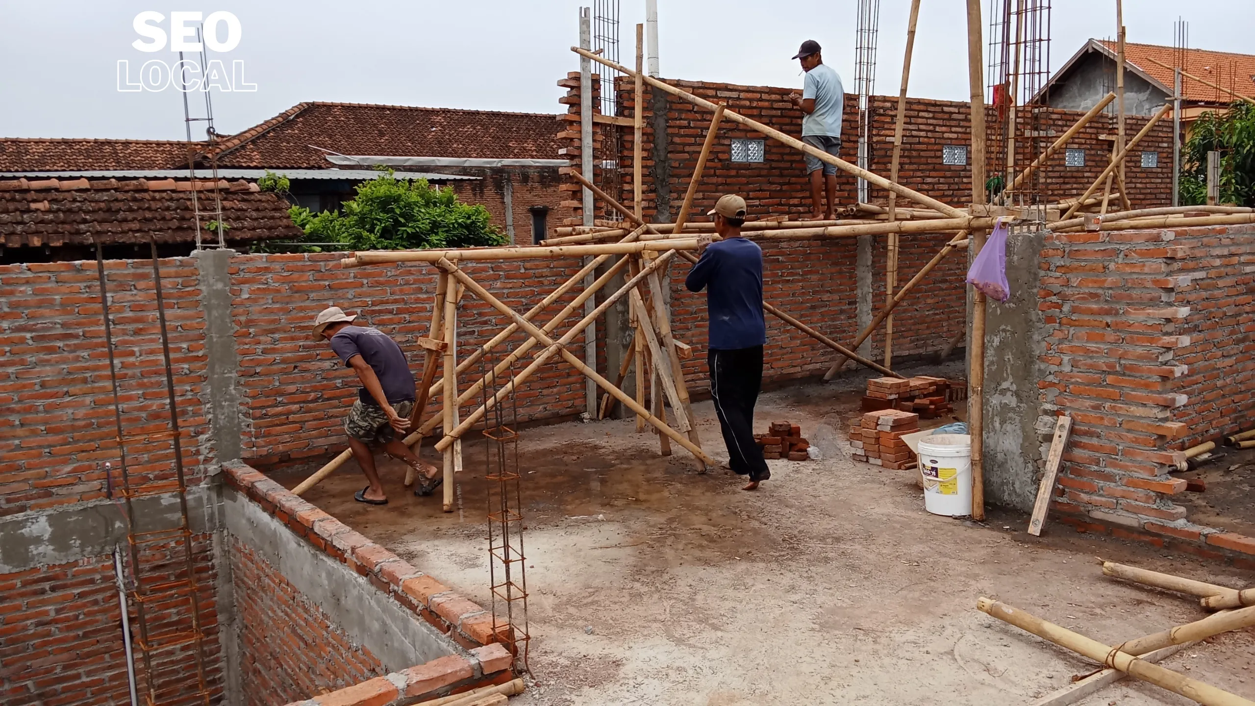 Obreros construyen un muro de ladrillo con andamios de madera