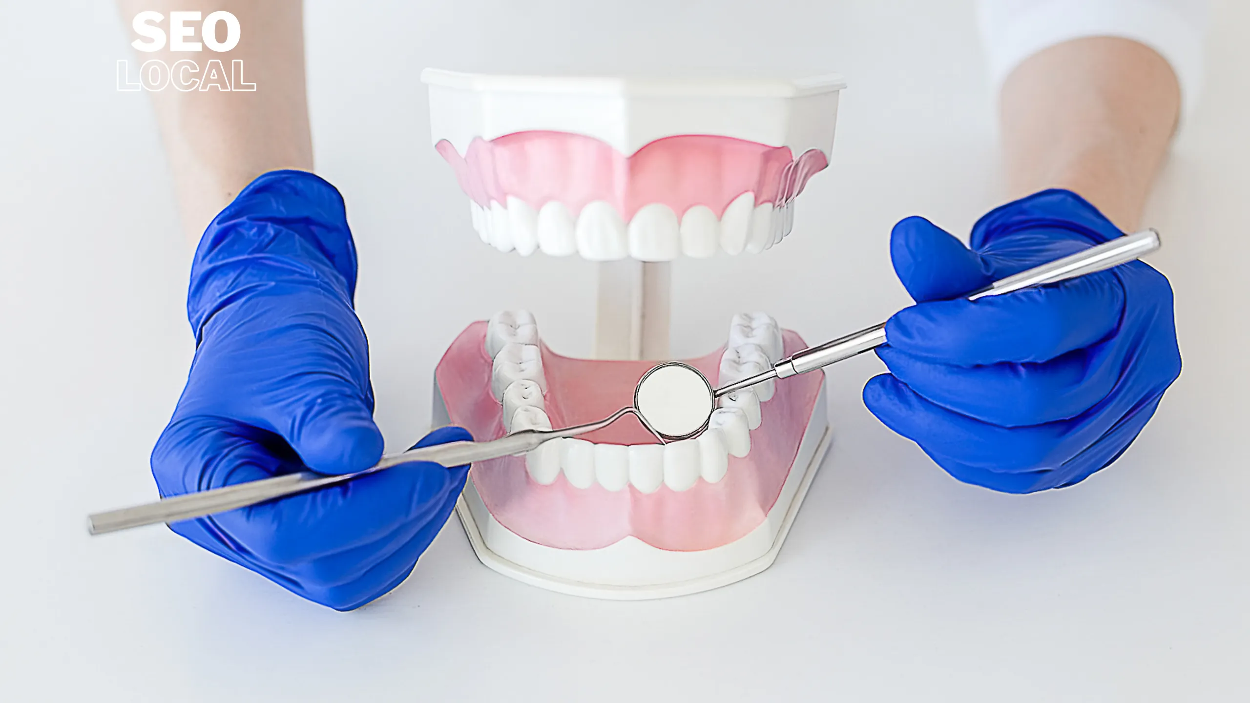 Manos con guantes azules revisan un modelo de dentadura con un espejo y una sonda